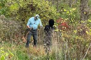 A SVTU volunteer, assisted by a St. James student are putting tree cages around shrubs